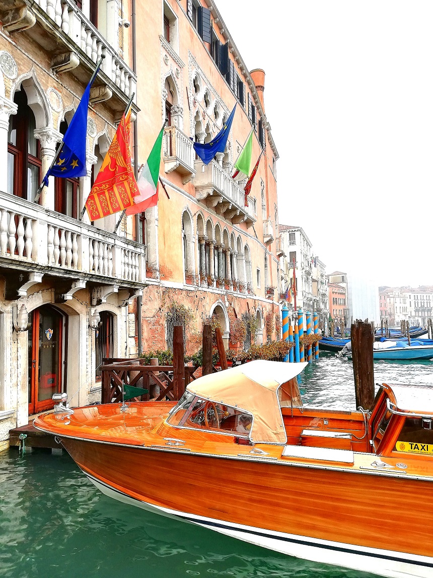 Bandiere e barca nel canale di Venezia